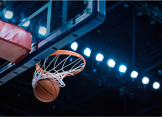 Basketball hoop with a ball successfully resting in the basket, showcasing a moment of scoring in the game.