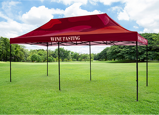 A wine tasting tent set up in a field surrounded by trees, inviting guests to enjoy a serene outdoor experience.