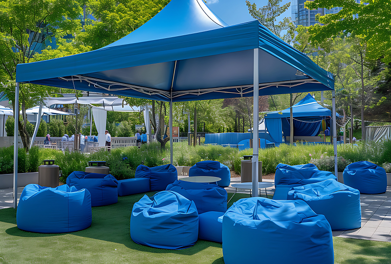 A blue tent set up with colorful bean bags and small tables, creating a cozy and inviting outdoor seating area.