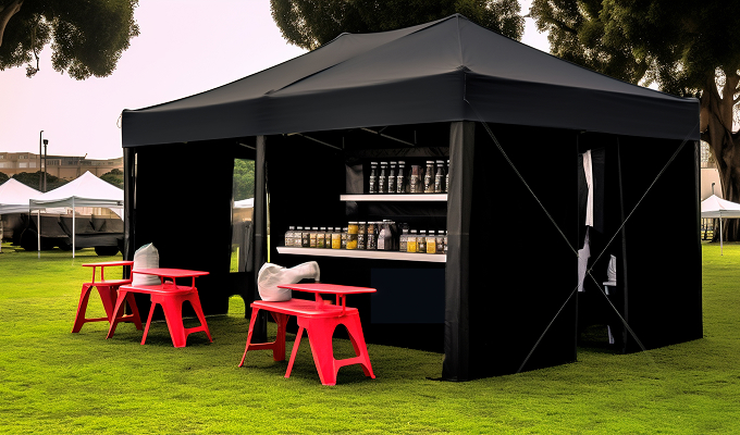 A black tent set up outdoors, furnished with red chairs and tables arranged neatly inside.