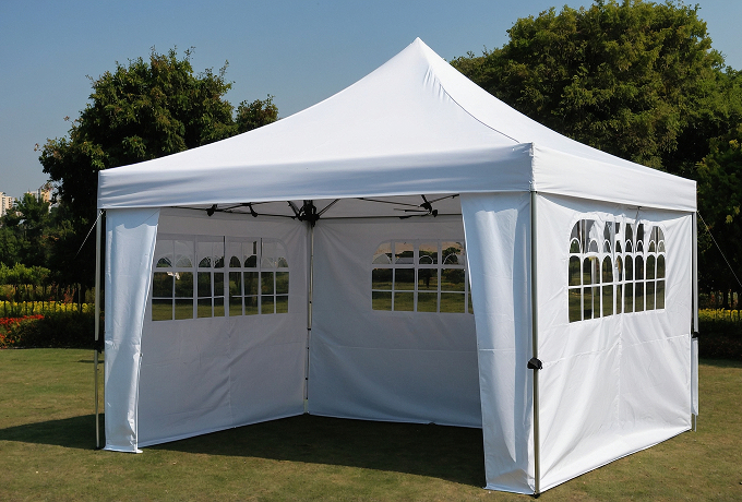 A white canopy tent set up on green grass, providing shade and shelter in an outdoor setting.