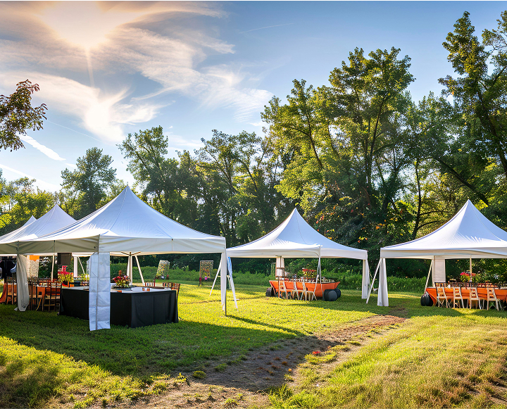 A large white tent is set up outdoors, surrounded by green grass, for a festive event with tables and chairs inside.