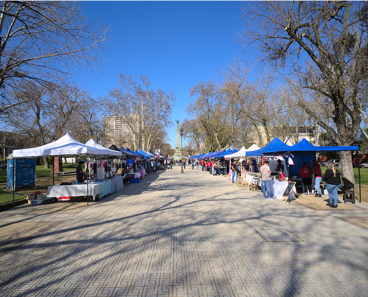 A bustling street filled with colorful tents and diverse groups of people engaging in various activities.