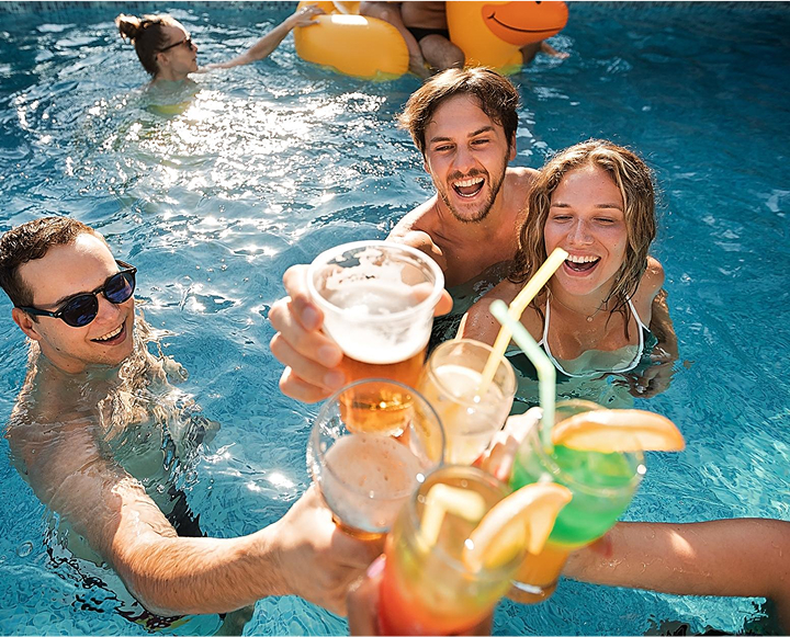 A group of people enjoying drinks while relaxing in a swimming pool on a sunny day.