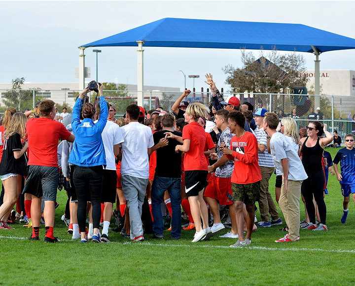 A group of people standing on a grassy field, engaged in a game of frisbee, enjoying a sunny day outdoors.