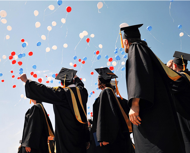 Graduates in caps and gowns joyfully hold colorful balloons, celebrating their achievements on graduation day.