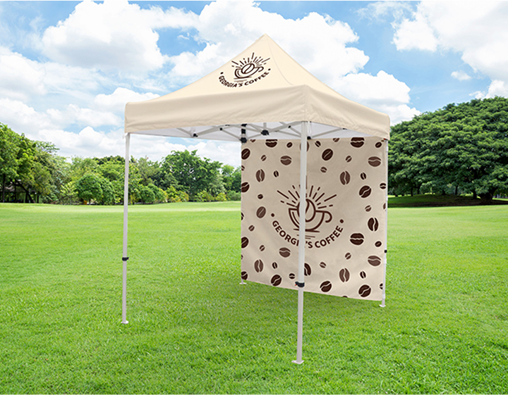 A coffee bean-shaped tent set up on a grassy field under a clear blue sky.