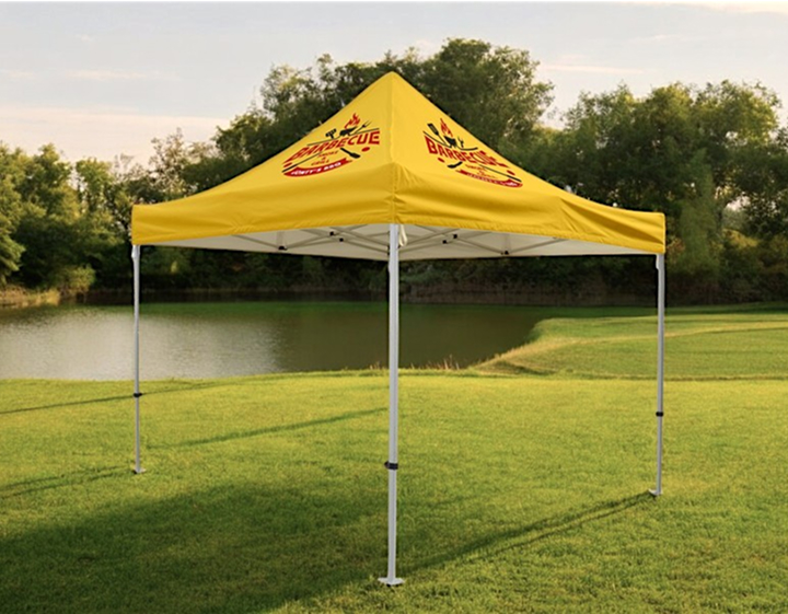 A yellow canopy tent set up on a grassy field under clear blue skies.